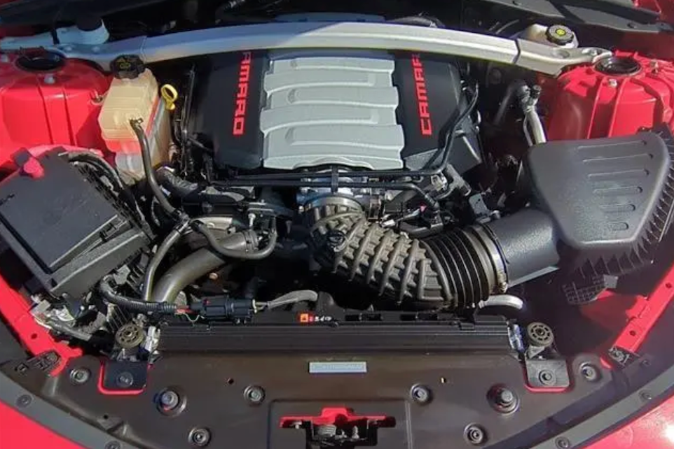Car engine with 'Camaro' branding on a red car