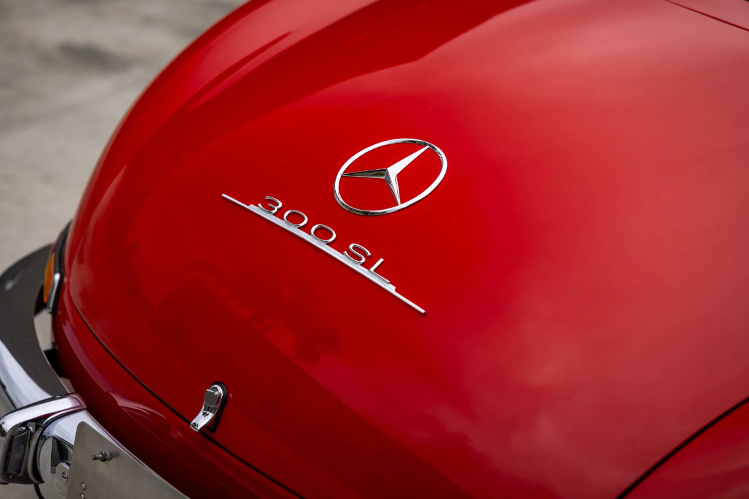 Close-up of a red Mercedes-Benz 300 SL car emblem on a blurred background