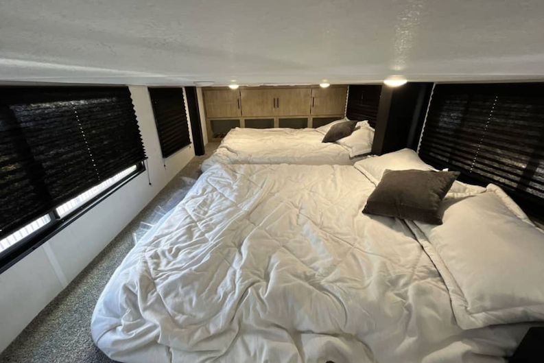 Bedroom interior with two beds and window blinds in a compact living space.