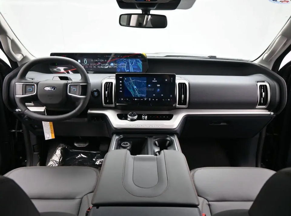 Car interior with steering wheel, dashboard, and center console.