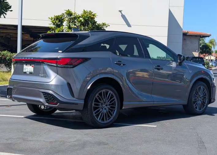 Silver SUV parked on a street with a building and trees in the background