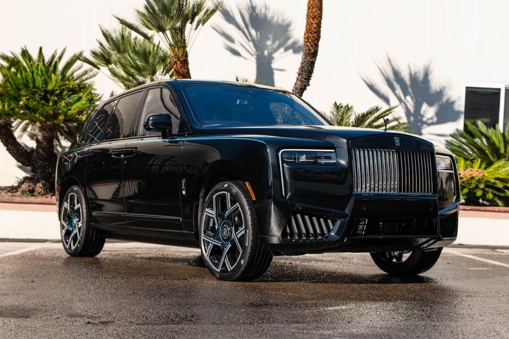 Black luxury SUV parked on a street with palm trees in the background