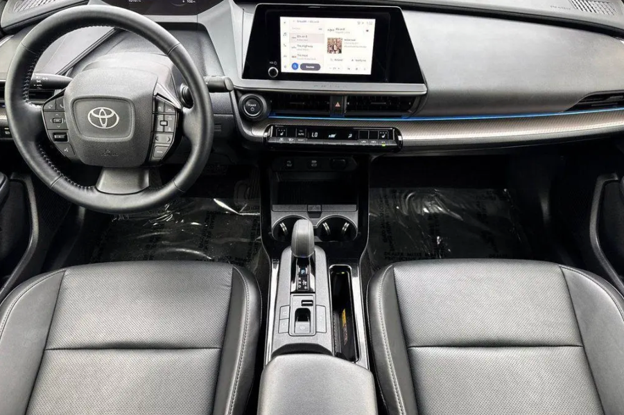 Car interior with steering wheel, dashboard, and center console.