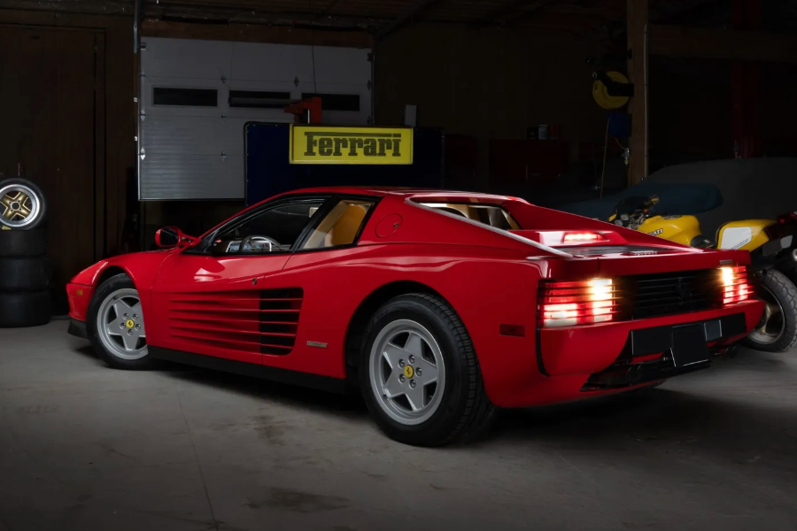 Red Ferrari sports car in a garage with 'Ferrari' branding on the wall.