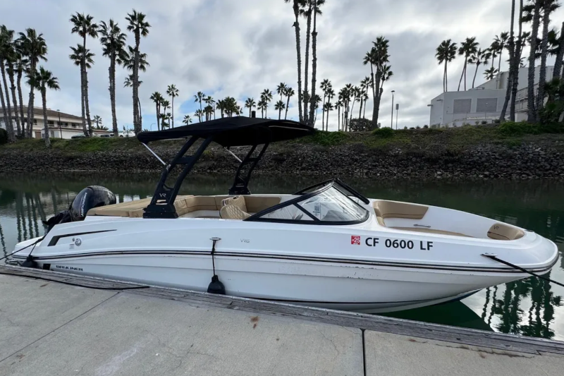 White boat with black top on a dock with palm trees in the background