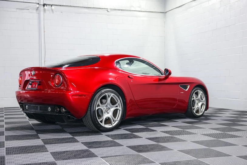 Red sports car on a checkered floor in a garage