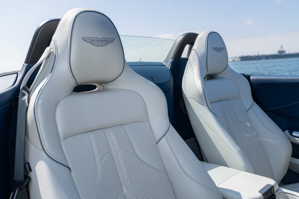 Luxury car interior with white leather seats and a visible brand logo.