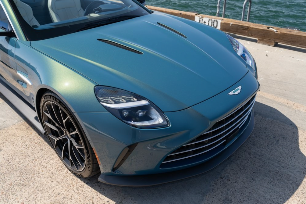 Blue sports car parked on a dock with water in the background
