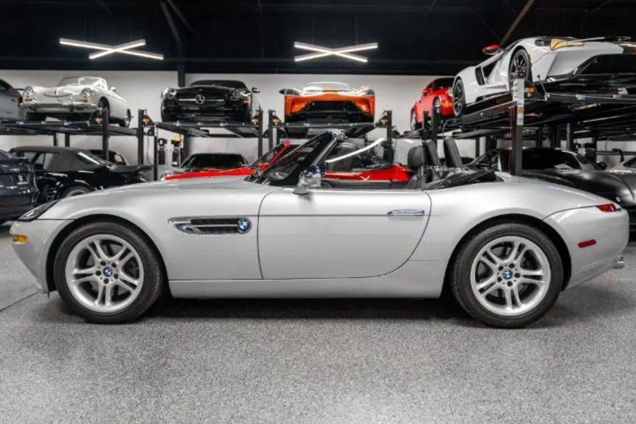 Silver BMW Z8 roadster in a showroom with other cars on lifts in the background