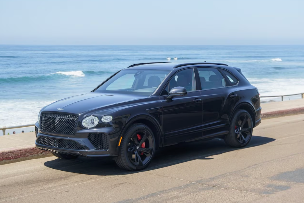 Black Bentley SUV parked on a road near the ocean