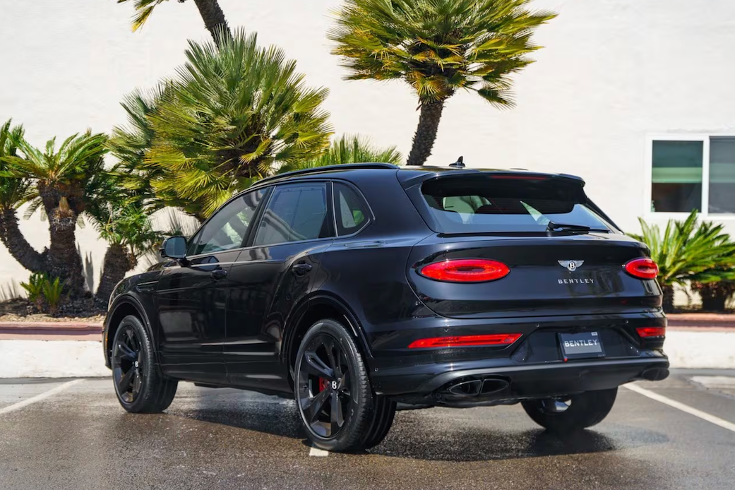 Black Bentley SUV parked in a lot with palm trees in the background