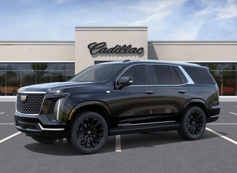 Black Cadillac SUV parked in front of a Cadillac dealership building.