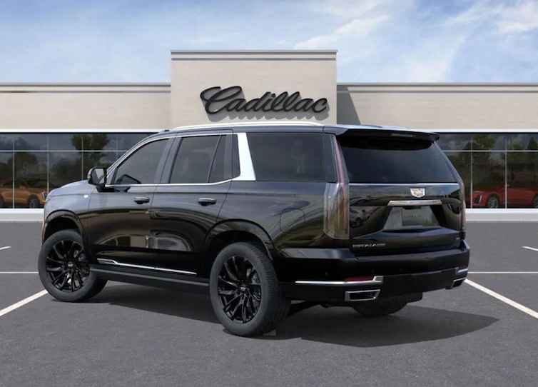 Black Cadillac SUV parked in front of a Cadillac dealership building.