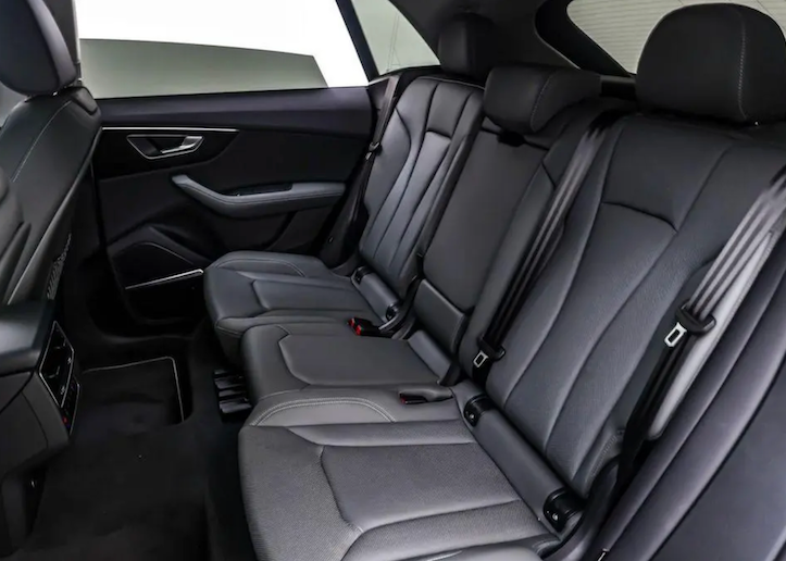 Back seat of a car with gray leather seats and visible door panel.
