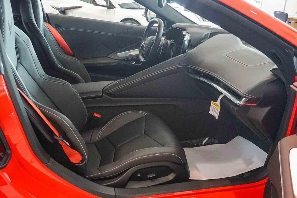 Car interior with open door showing black seats and dashboard.