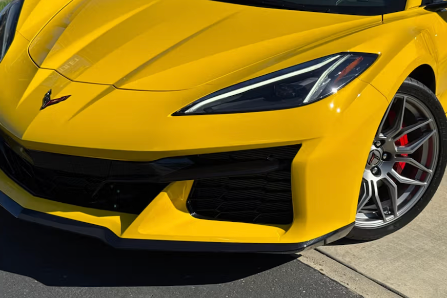 Yellow sports car with a close-up of the front grille and wheel on a pavement background