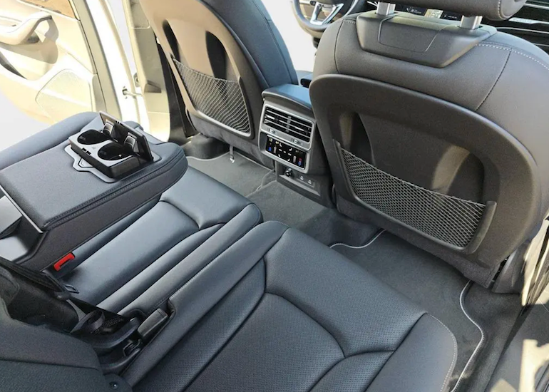 Car interior with gray seats and cup holders.