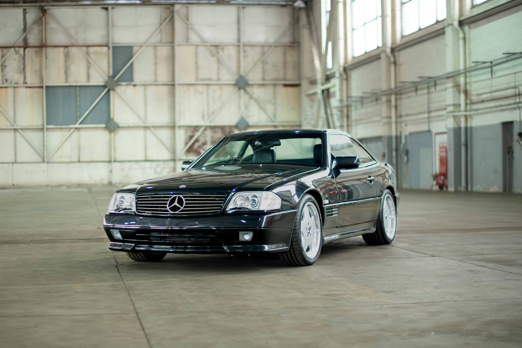 Black Mercedes-Benz car in a large industrial warehouse.