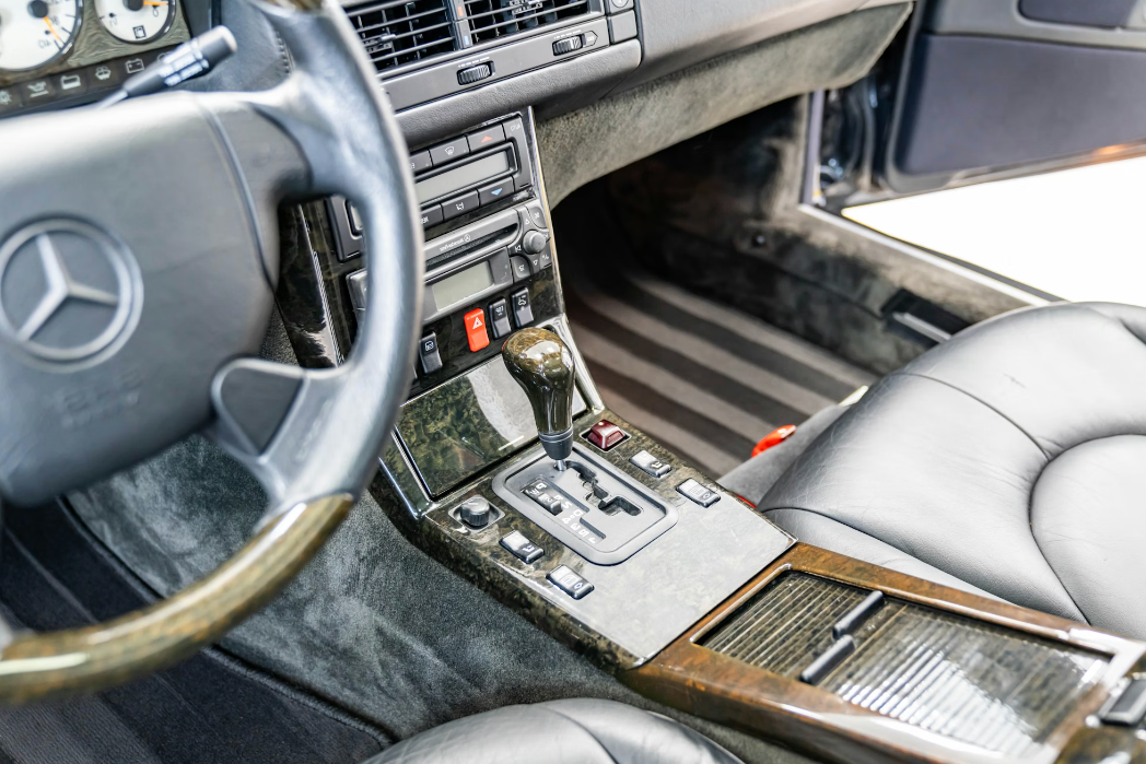 Car interior with steering wheel and dashboard featuring Mercedes-Benz logo.