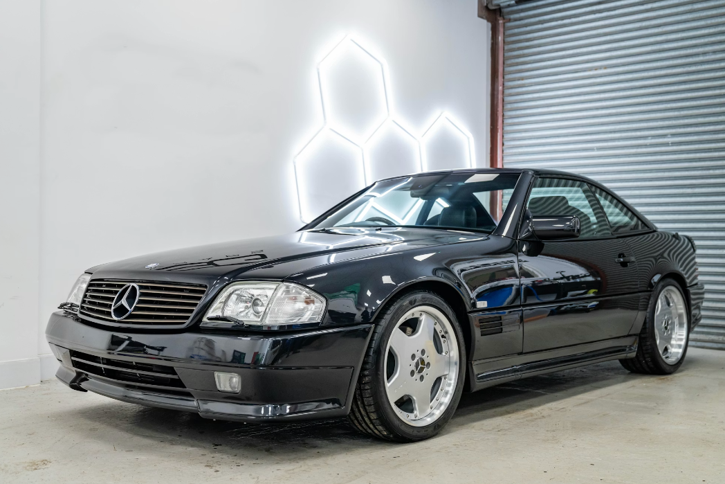 Black Mercedes-Benz car parked in a garage with a neon light in the background