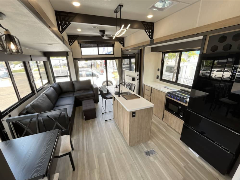 Interior of a modern RV with living area, kitchen, and dining table.