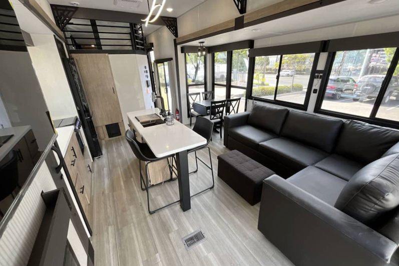 Modern living room with gray sectional sofa, dining table, and large windows.