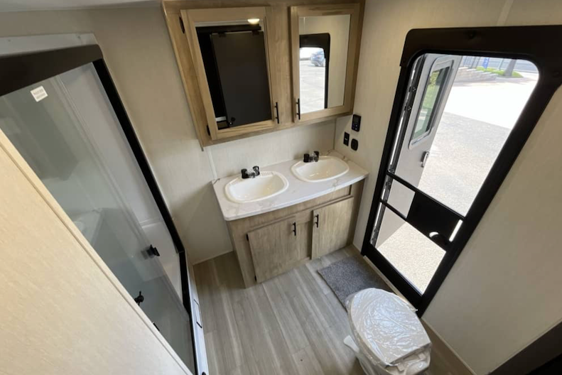 Compact bathroom inside a recreational vehicle with vanity, sink, and mirror.