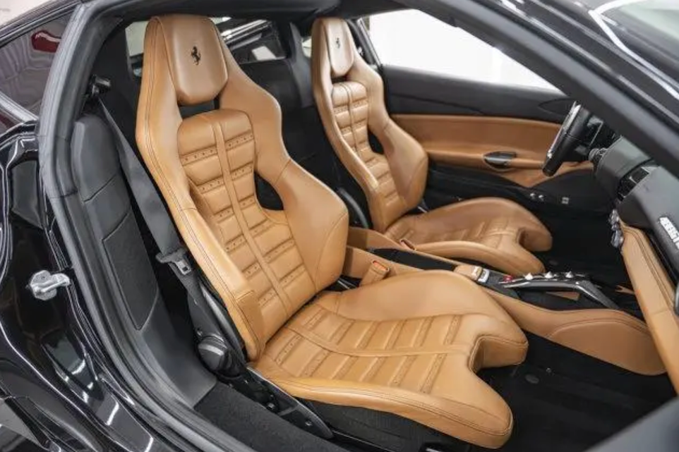 Beige leather seats inside a luxury car with visible Ferrari logo.