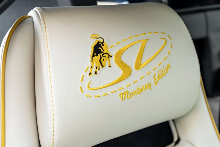 Car seat headrest with embroidered logo and text in a vehicle interior.