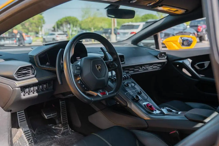 Luxury car interior with steering wheel and dashboard, featuring a prominent logo.
