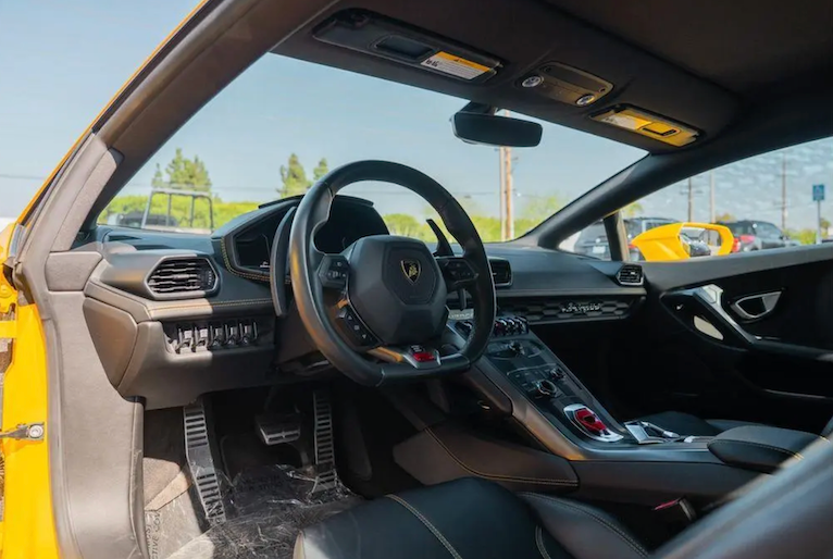 Car interior with steering wheel and dashboard, showing brand logo, with outdoor background.