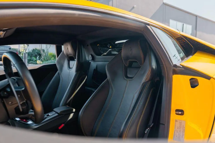 Close-up of a car's interior with black seats and yellow exterior.