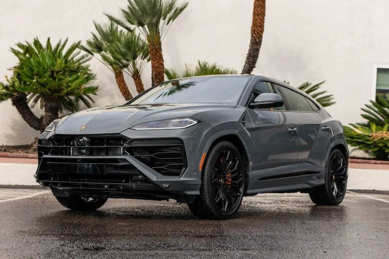 Gray Lamborghini SUV parked on a street with palm trees in the background