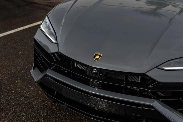 Close-up of a Lamborghini car front with logo on a road.