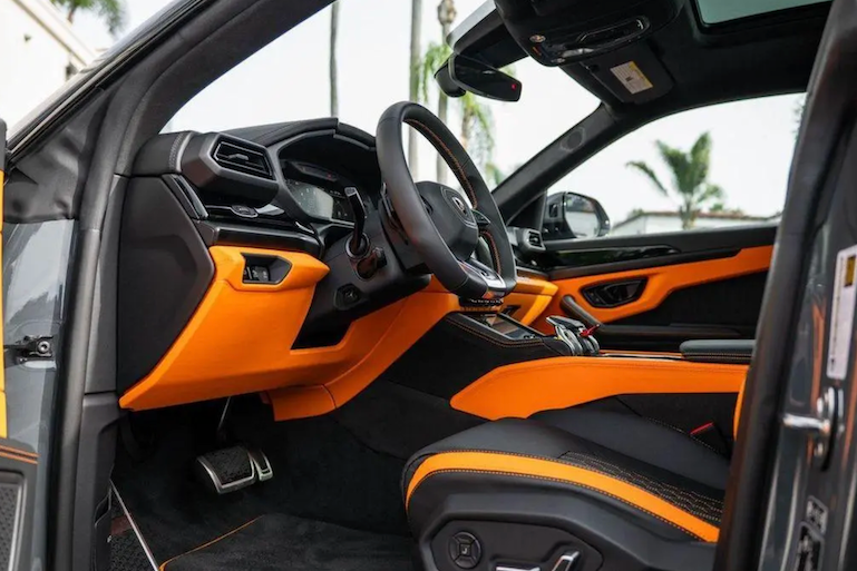 Car interior with orange and black design, including steering wheel and dashboard.