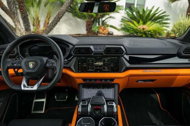 Luxury car interior with orange and black design, featuring a prominent Lamborghini logo.