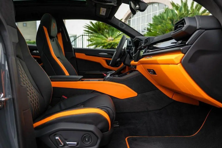 Car interior with black and orange seats and dashboard.