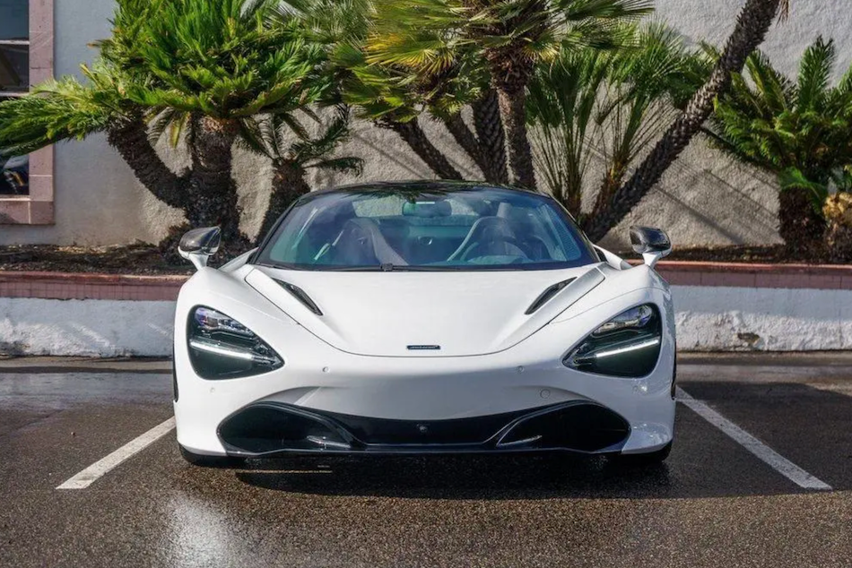White sports car parked in a parking lot with palm trees in the background