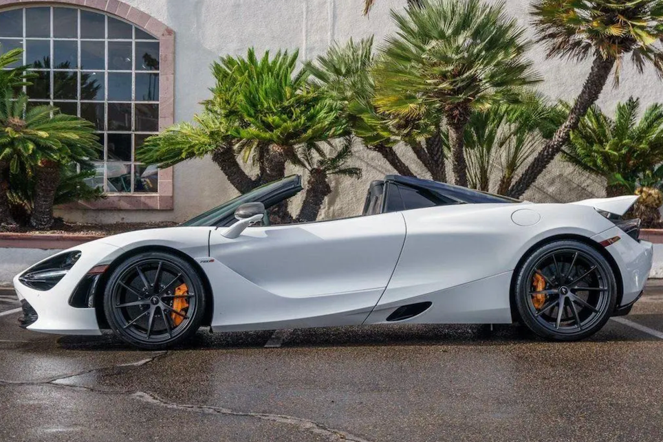 White sports car parked on a wet street with palm trees in the background