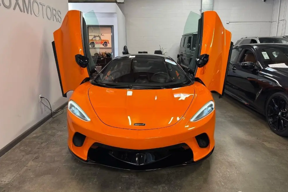 Orange sports car with open doors in a showroom setting