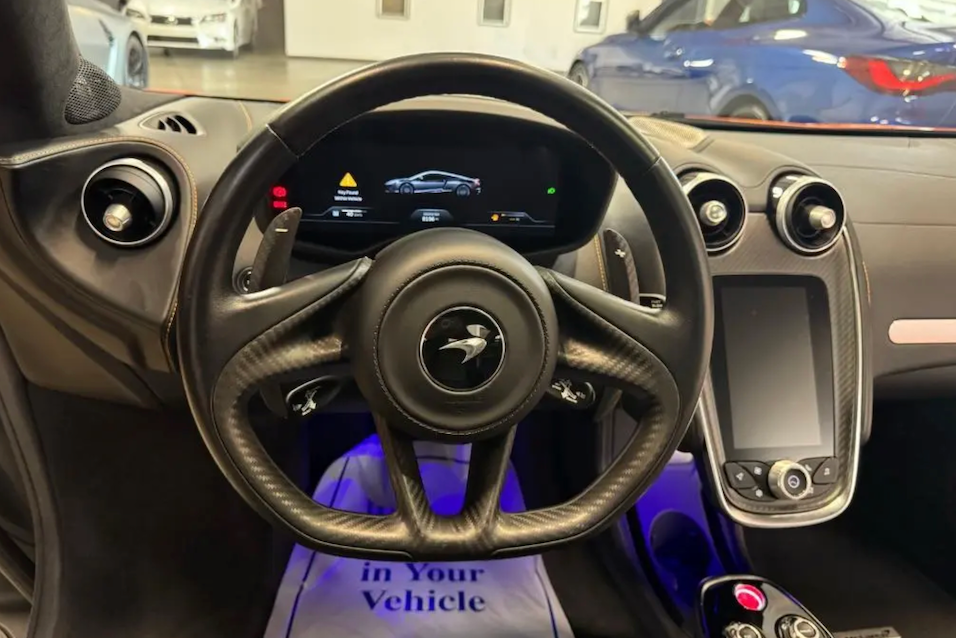 Car interior with steering wheel and dashboard, showing a warning message.