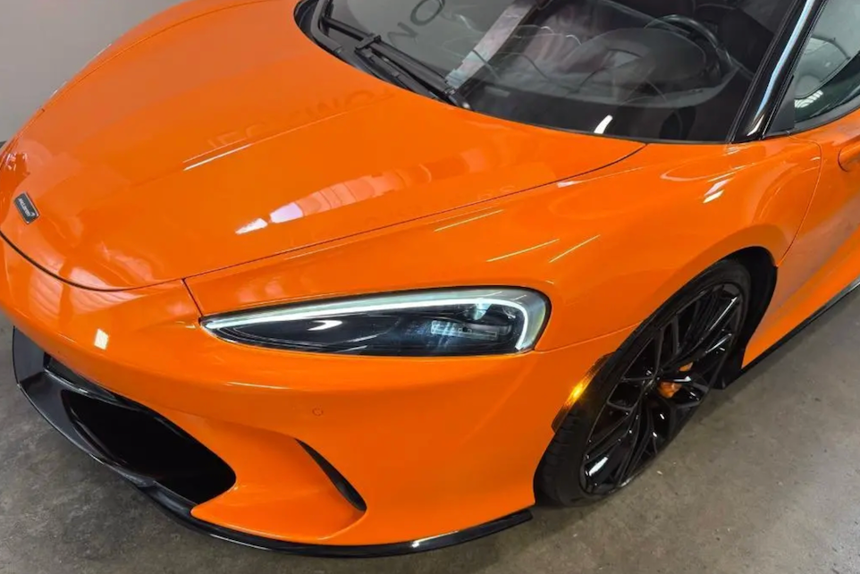 Orange sports car with black rims on a concrete floor