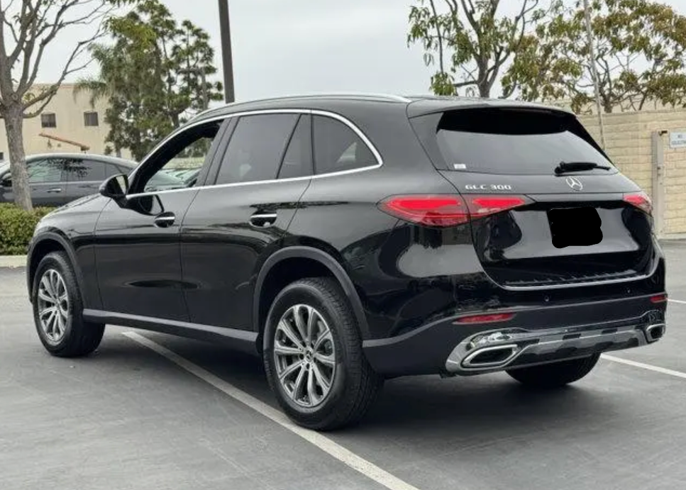 Black Mercedes-Benz SUV parked on a street with trees and buildings in the background