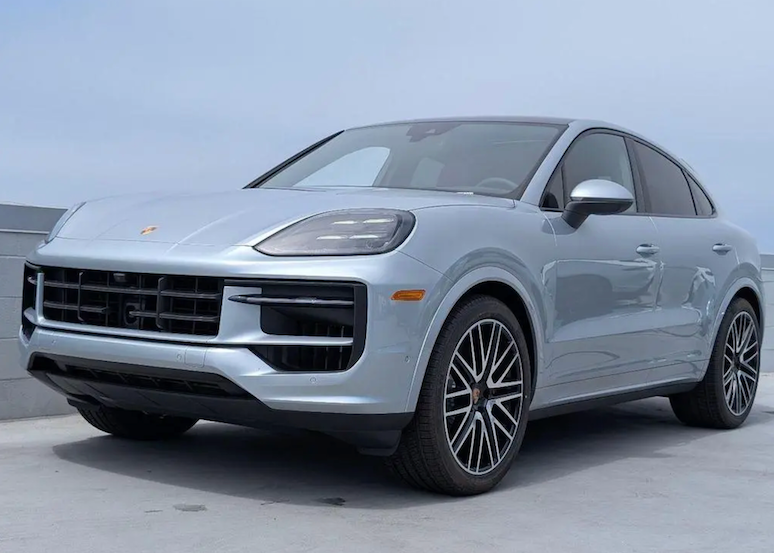 Silver Porsche SUV parked on a gray surface with a light blue sky background
