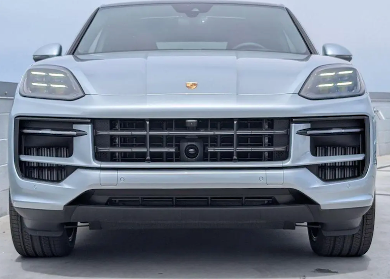 Front view of a Porsche SUV with a light gray color on a plain background