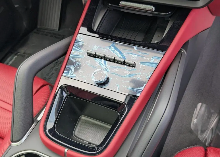 Car interior with red and black design, including a cup holder and air vent.