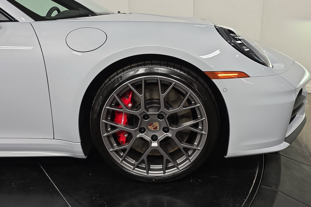 Close-up of a car wheel with a gray rim and red brake caliper on a white background