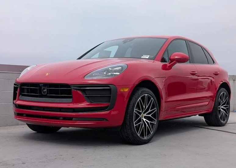 Red Porsche SUV parked on a gray surface with a neutral background