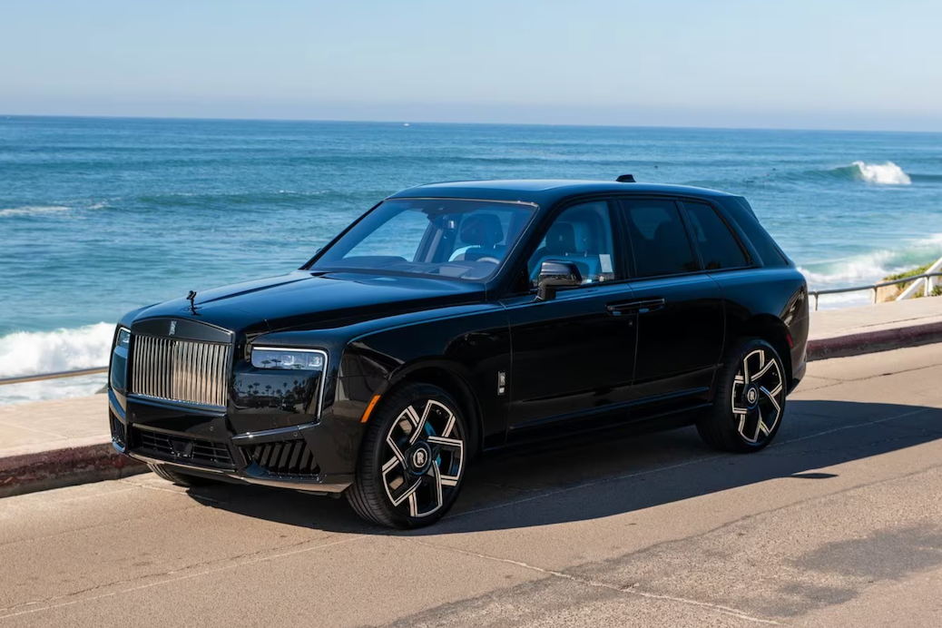 Black luxury SUV parked by the ocean with waves crashing in the background