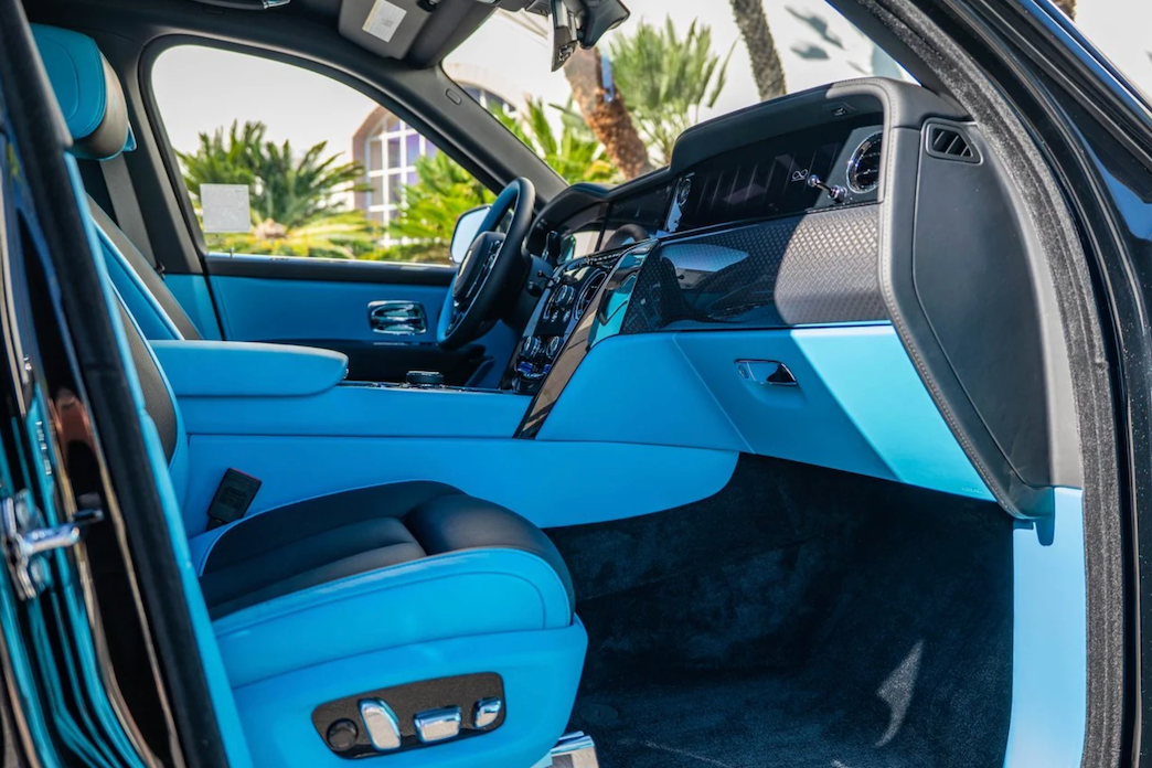 Luxury car interior with blue seats and dashboard, palm trees in the background